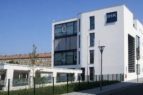 Gebäude der IHK Halle-Dessau Geschäftsstelle Dessau, moderner weißer Neubau mit IHK-Schild, blauer Himmel